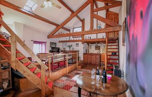 Ein rustikales Interieur mit freiliegenden Holzbalken, einer Treppe, einem Essbereich und einer Küche.