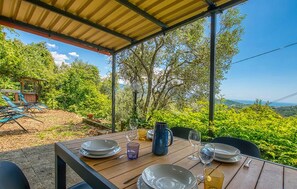 An outdoor dining area with a table set for four, surrounded by lush greenery and a clear view of the landscape. - Amazing home in Rapallo with house sea view (Rapallo)