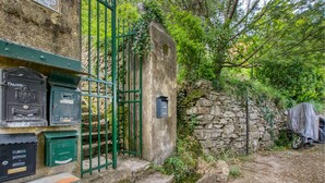 Un mur de pierres apparentes, un portail en métal et des boîtes aux lettres d’époque.