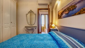 Une chambre à coucher avec un lit, une commode, un miroir, une table de chevet et un tableau accroché au mur.