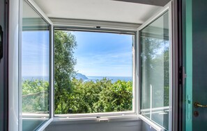 A room with a large window offering a view of a forest and a distant mountain. - Cozy home in Pieve Ligure with WiFi (Pieve Ligure)