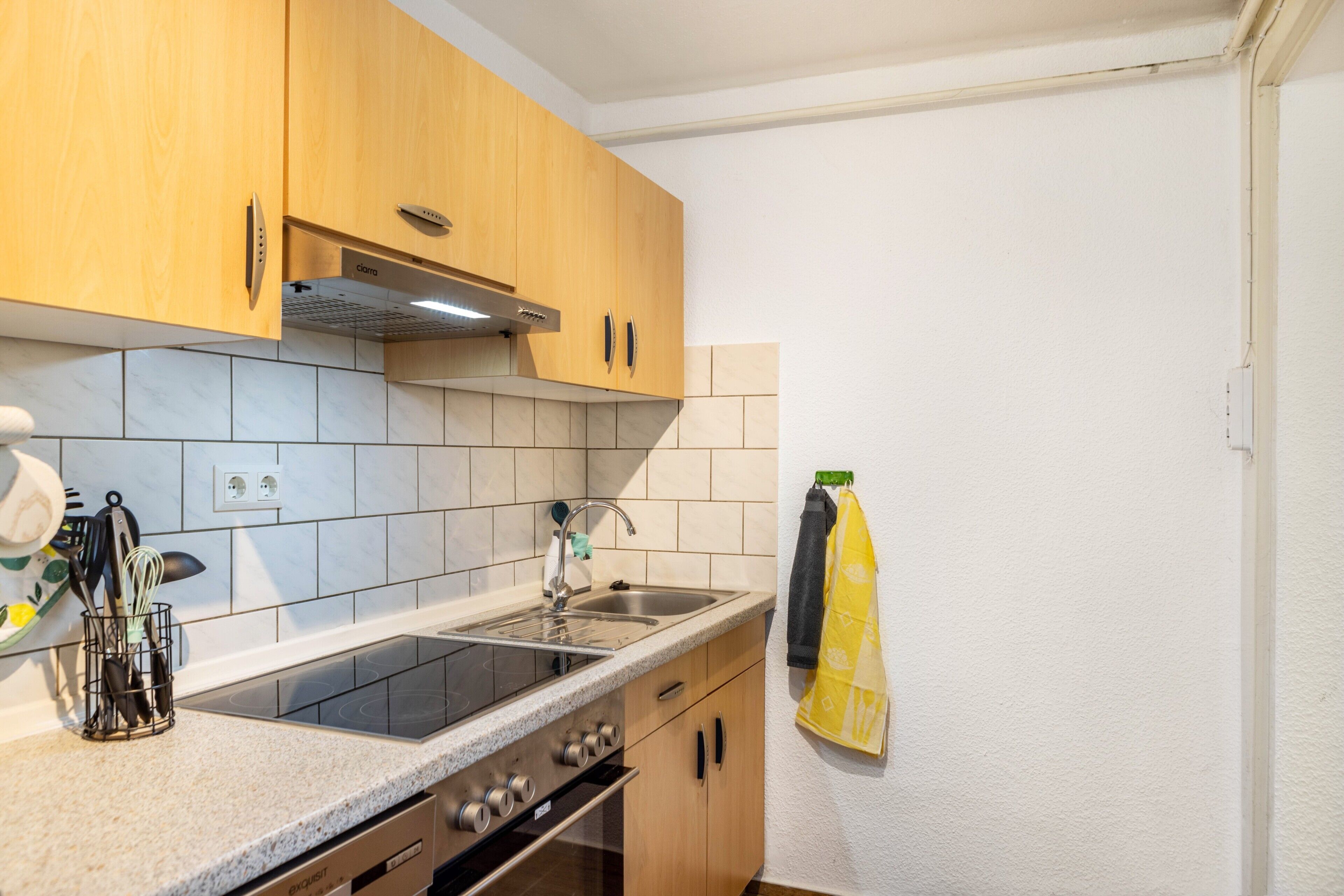 Una cocina con armarios de madera, un lavamanos de acero inoxidable y un horno empotrado.