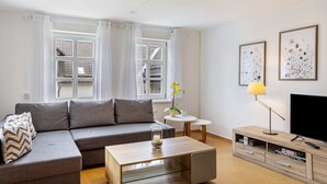 A modern living room with a sofa, coffee table, TV stand, and artwork. - Apartment 'Fewo Am Uplandsteig' with Shared Terrace, Garden and Wi-Fi (Diemelsee)