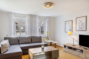 A modern living room with a sofa, coffee table, TV stand, and artwork on the walls.