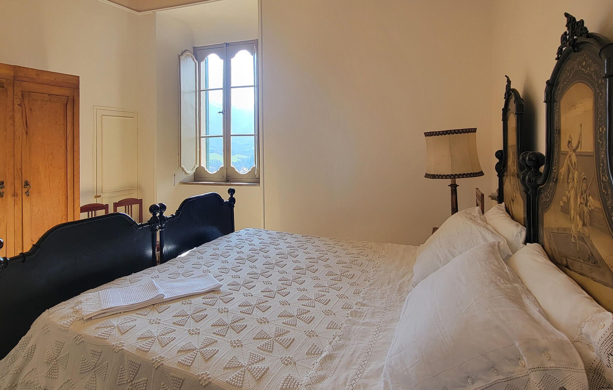 Un dormitorio con cama, un armario de madera, una ventana y un espejo.