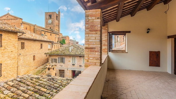 Un patio con un edificio de ladrillo, una escalera de piedra y vistas a una torre.