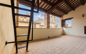 Ein Zimmer mit einer Holzleiter, einem Kachelboden und Blick auf historische Gebäude durch ein Fenster.