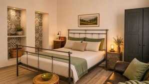 Een slaapkamer met een metalen bedframe, een nachtkastje met een lamp, een houten kast en een groene bank.