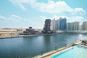 Ein Hotel am Wasser mit Pool, Blick auf die Skyline der Stadt und einem Yachthafen.