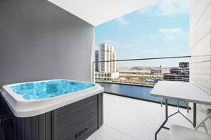 Ein Balkon mit Whirlpool, einem Tisch und Blick auf eine Marina sowie Gebäude.