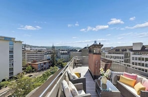 A rooftop terrace with outdoor seating, a view of the cityscape, and a prominent tower structure. - Waterfront Penthouse | AC | Rooftop | Free Parking (Zürich)
