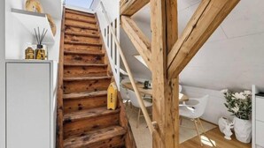 A wooden staircase leading to a white interior space with a dining area and a white chair. - Waterfront Penthouse | AC | Rooftop | Free Parking (Zürich)