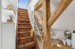 A wooden staircase leading to a white interior space with a dining area and a white chair. - Waterfront Penthouse | AC | Rooftop | Free Parking (Zürich)