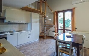 Eine Küche mit weißen Schränken, einem Esstisch mit Stühlen und einer Treppe, die in einen oberen Stock führt.