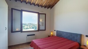 A bedroom with a bed, a window with a view, a radiator, and a nightstand with a lamp. - Lovely apartment in Montescudaio with WiFi (Montescudaio)
