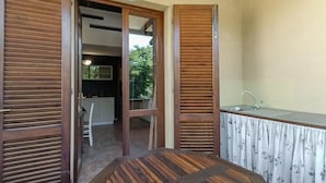 A room with a wooden table, a kitchen area with a sink, and a sliding door leading to another room. - Lovely apartment in Montescudaio with WiFi (Montescudaio)
