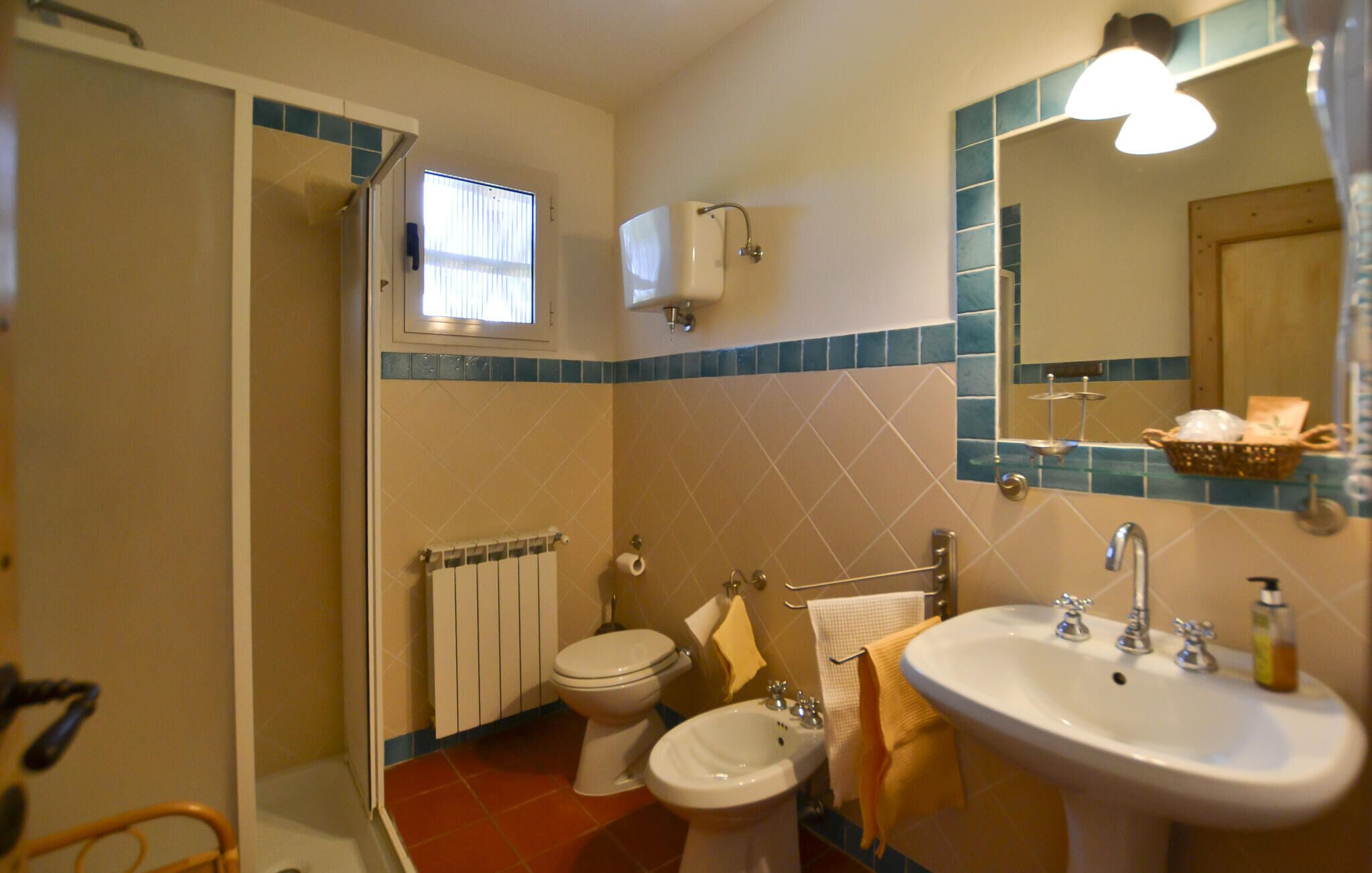 A bathroom with a toilet, bidet, sink, and a mirror with a towel rack.