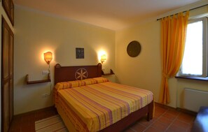 A bedroom with a bed, two wall-mounted lamps, a small painting, a round mirror, and a window with curtains. - 2 bedroom awesome home in Pietralunga (Pietralunga)