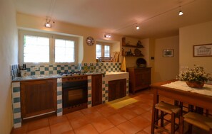 A kitchen with a stove, oven, sink, and a dining area with a table and chairs. - 2 bedroom awesome home in Pietralunga (Pietralunga)