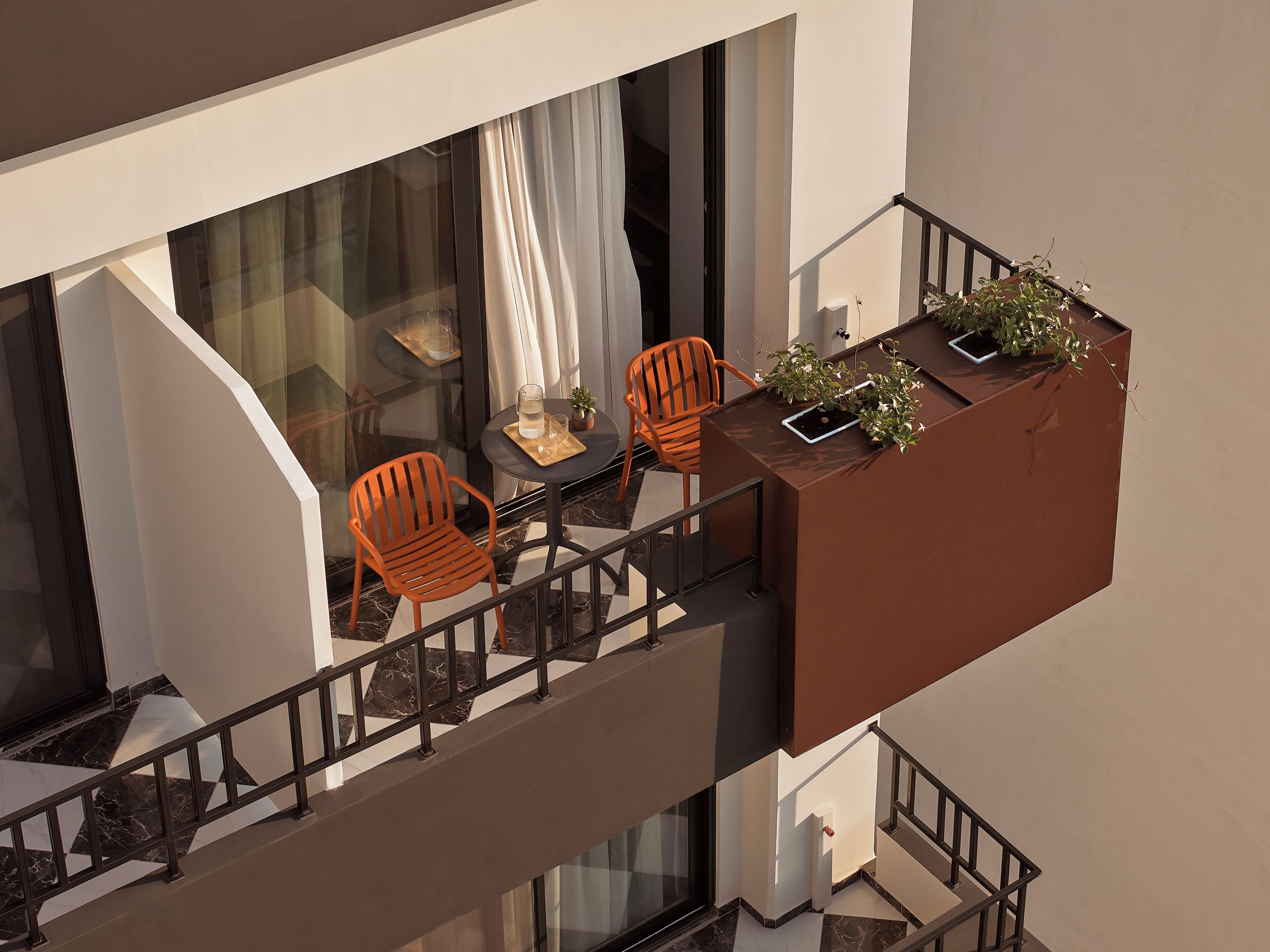 A balcony with a table, two chairs, and potted plants.