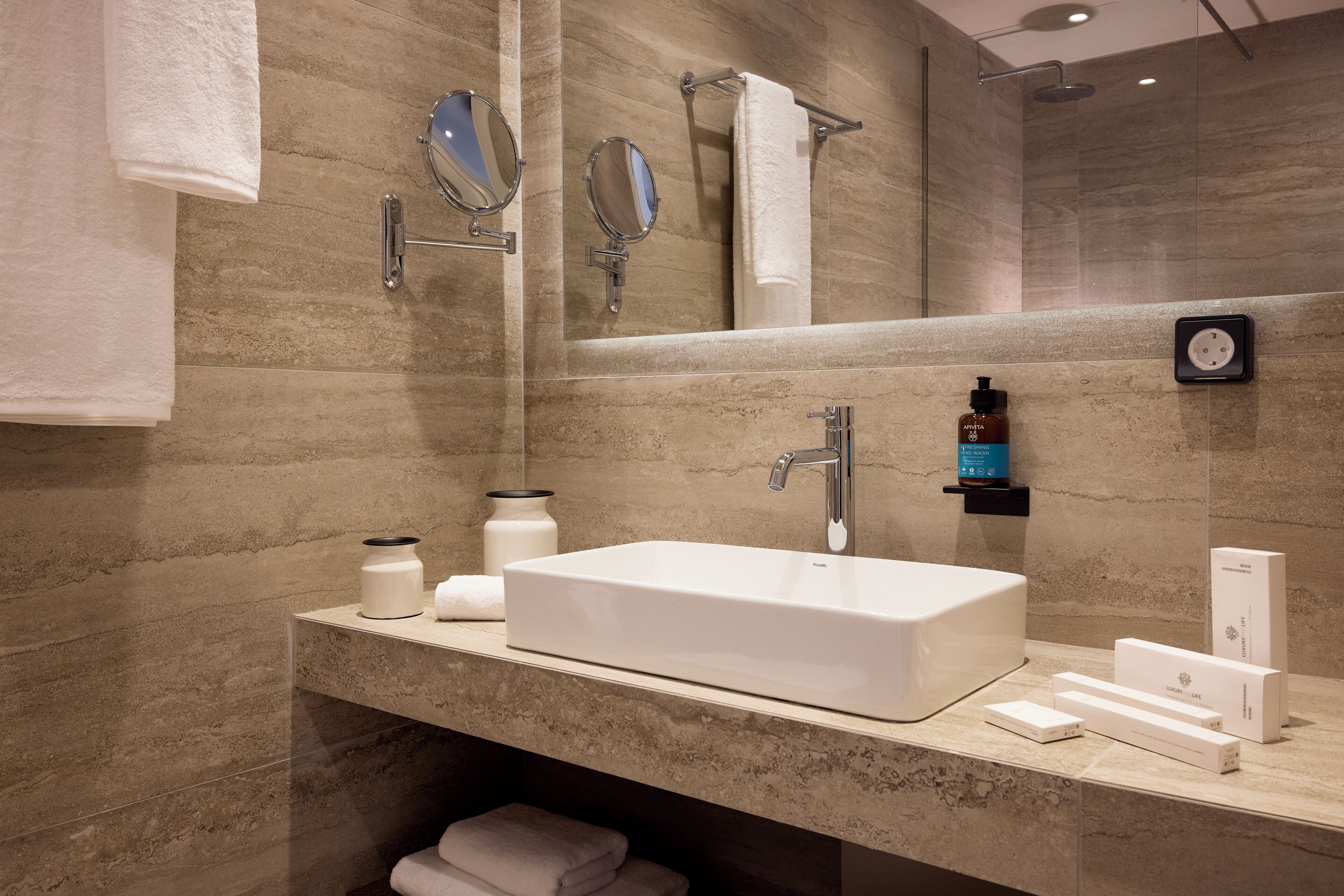 A modern bathroom with a large mirror, a white sink, and a towel rack.