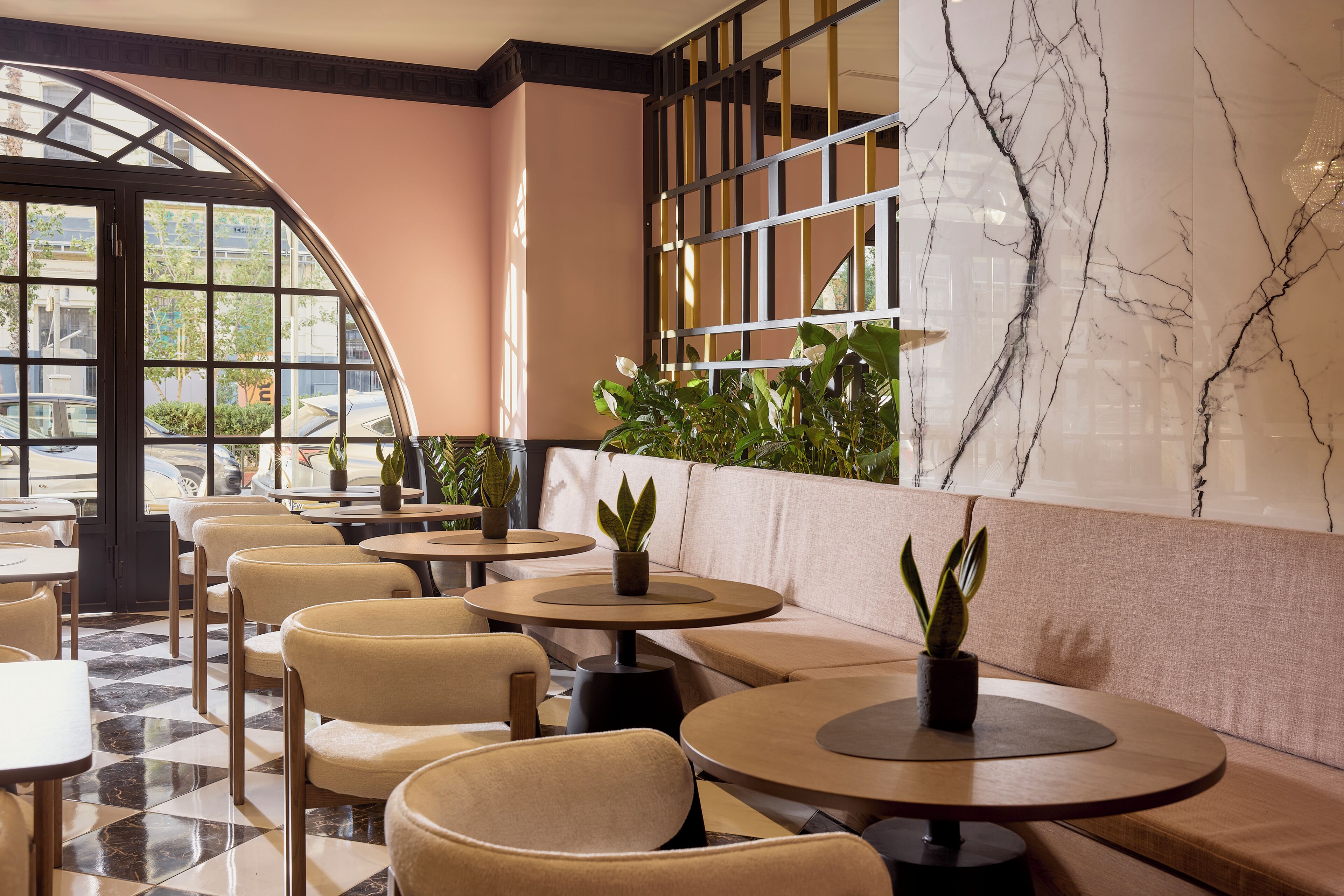 Un restaurant avec des tables rondes, des sièges rembourrés et des plantes en pot.