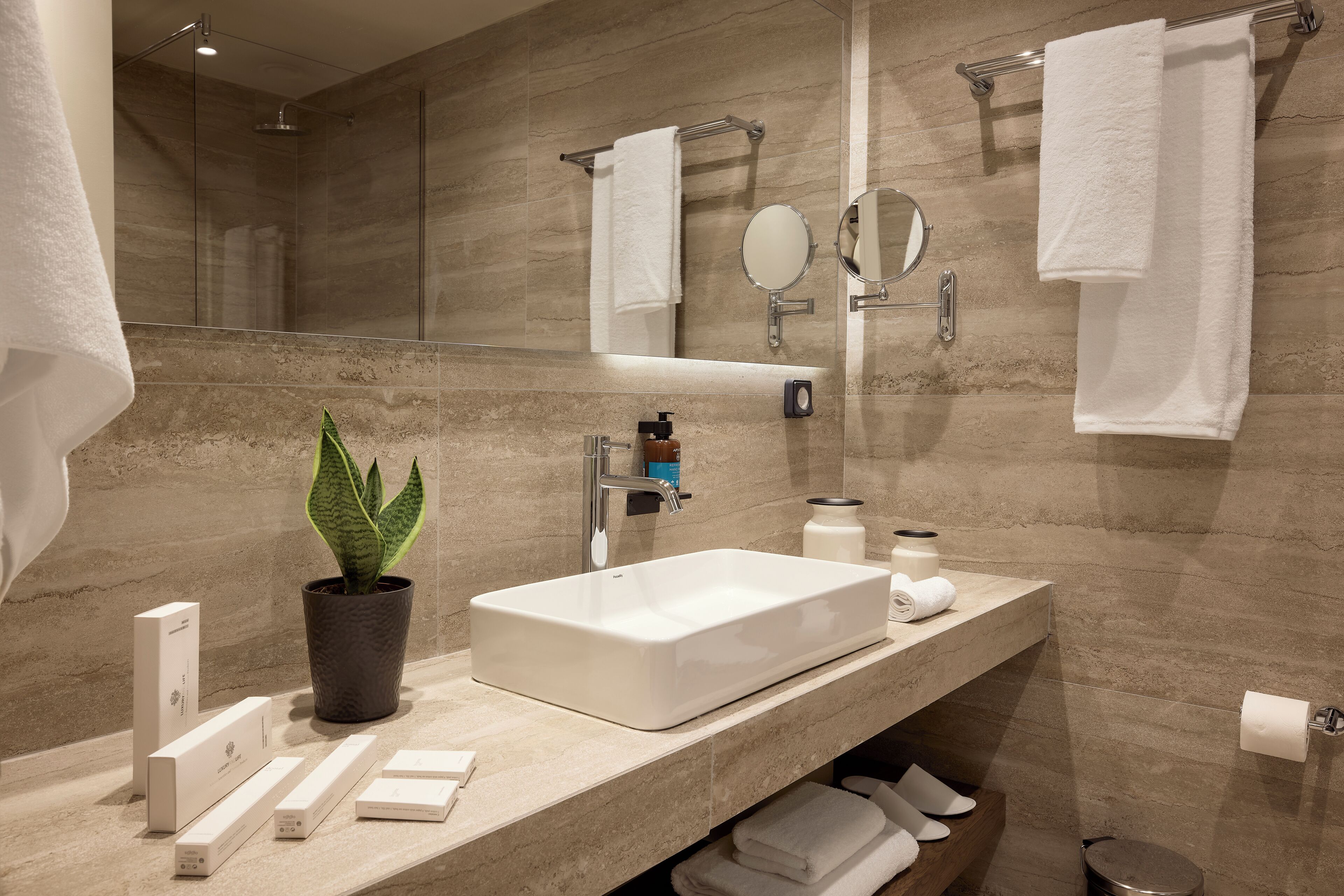 A modern bathroom with a large mirror, a sink, and a shower.