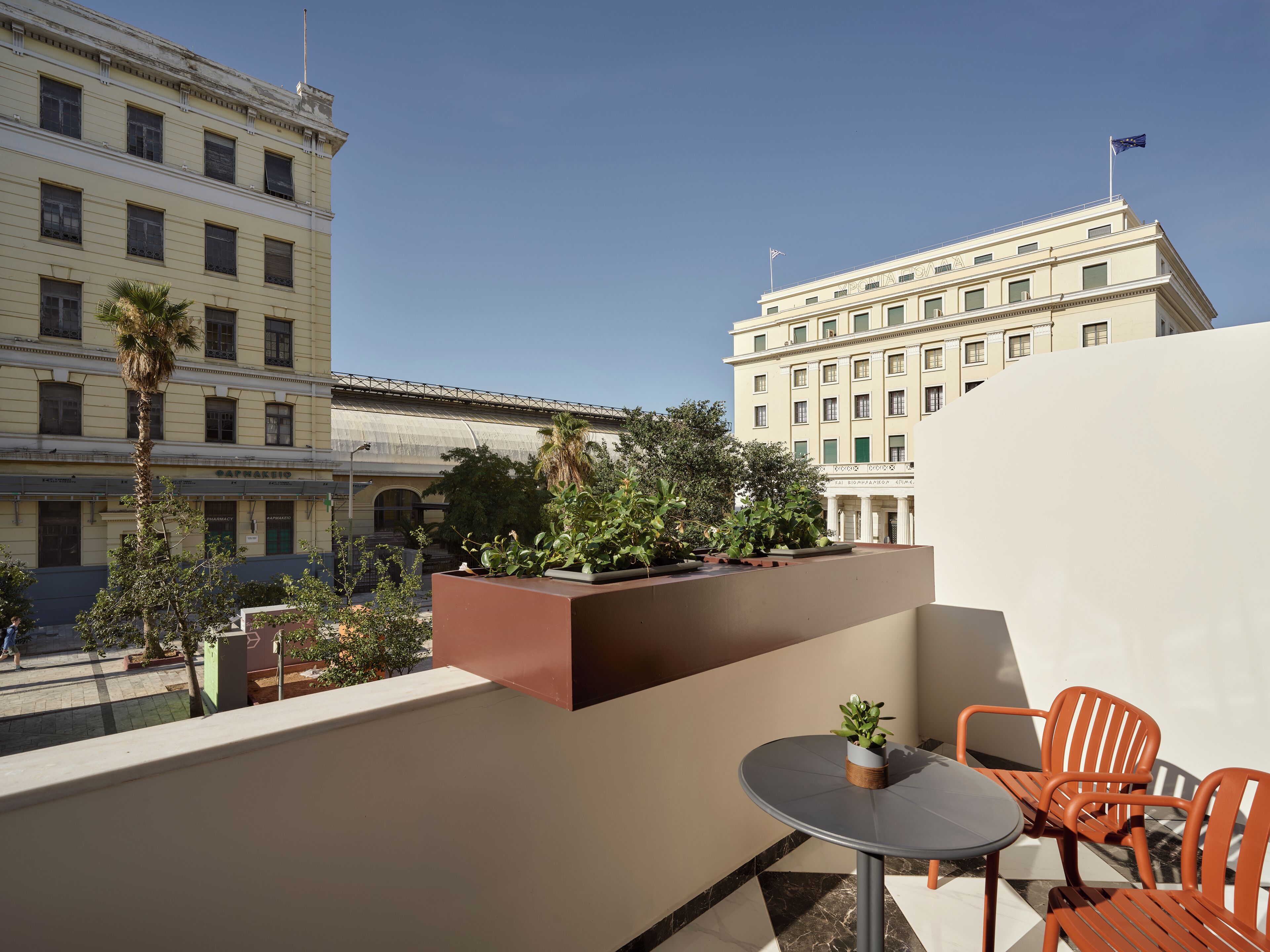 A rooftop terrace with a table and chairs, potted plants, and a view of historic buildings.