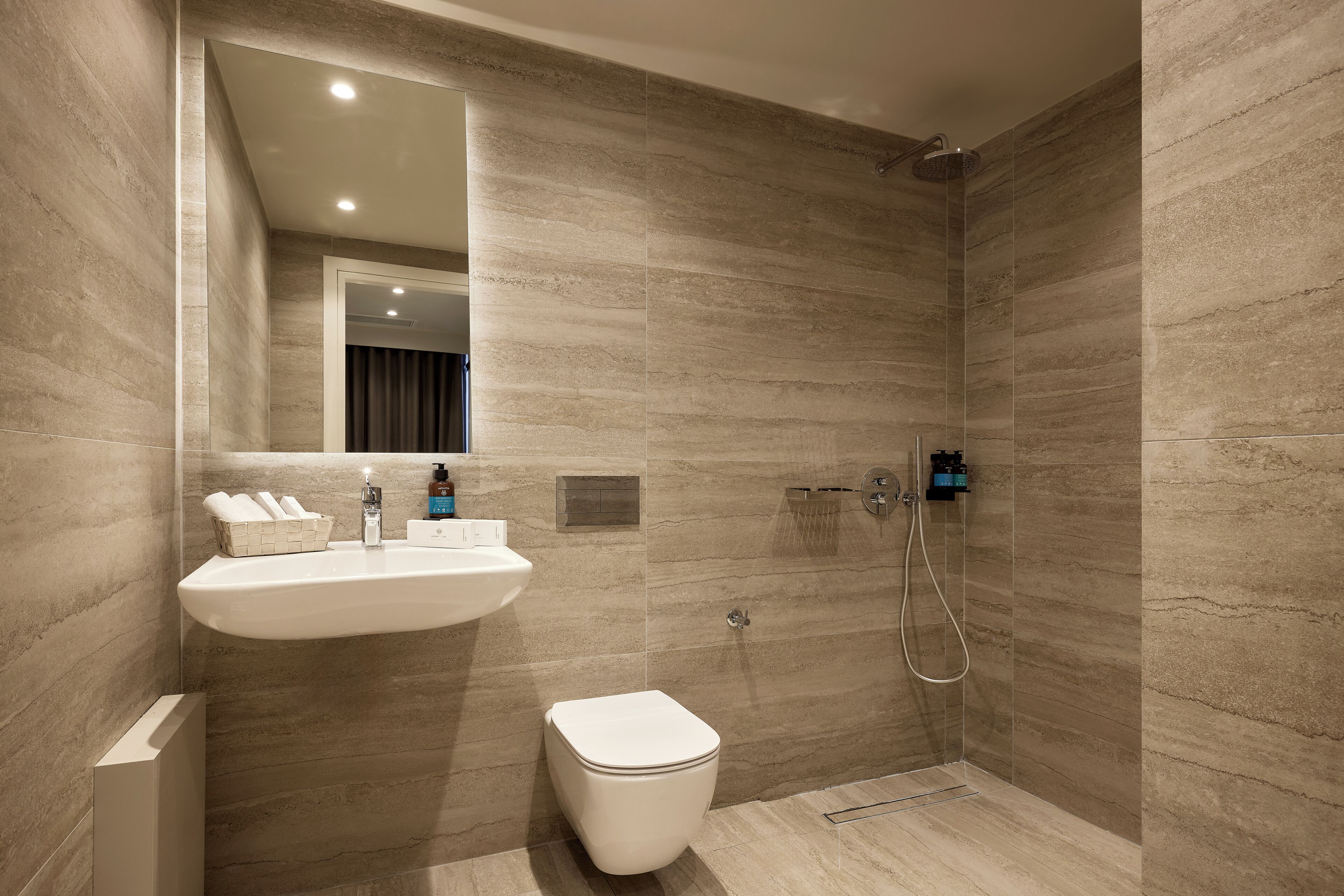 A modern bathroom with a shower, sink, and toilet.