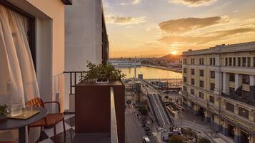 A balcony with a view of a river, a cityscape, and a building with columns.