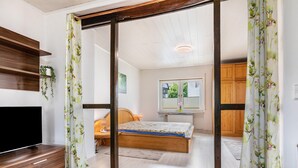 A bedroom with a bed, a TV, wooden furniture, and a window.