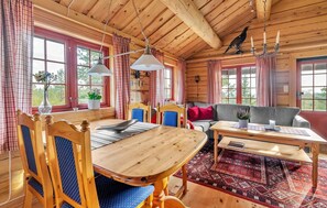 A wooden cabin interior with a dining table, chairs, a sofa, and a chandelier. - Beautiful home in Evje with WiFi (Evje)