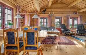 A wooden cabin interior with a dining area, two chairs, a sofa, a table, and a rug. - Beautiful home in Evje with WiFi (Evje)