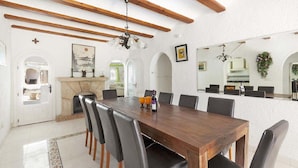 A dining area with a wooden table and chairs, a fireplace, and a large mirror. - Villa Perlita Javea, large villa with private pool, wifi and airconditioning. (Jávea)