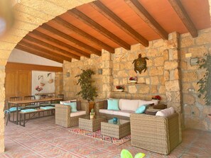 Une pièce aux murs de pierre, avec un plafond en bois, des meubles en osier, un coin repas et une décoration sur le thème des tortues.