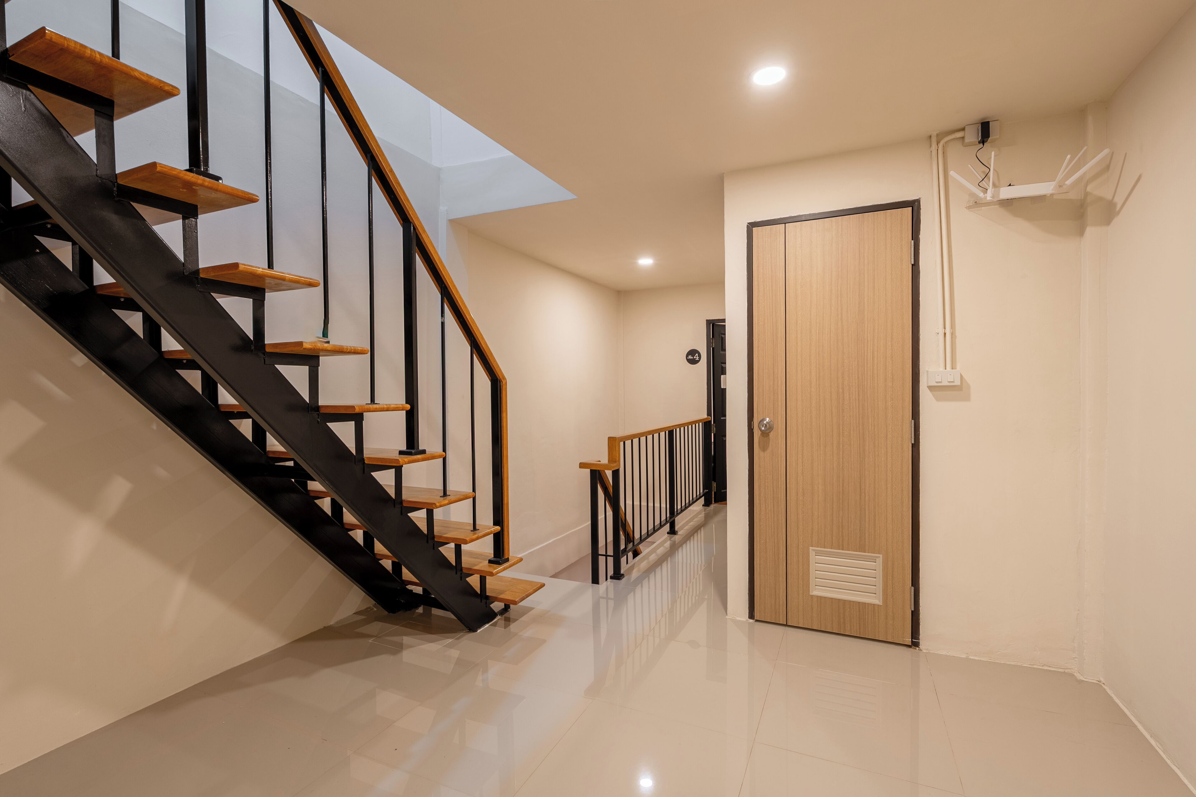 A modern interior with a staircase, a wooden door, and a ceiling-mounted device.