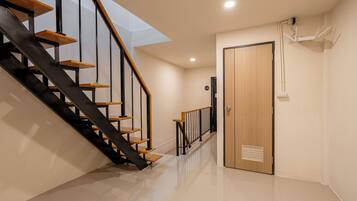 A modern interior with a staircase, a wooden door, and a ceiling-mounted device.
