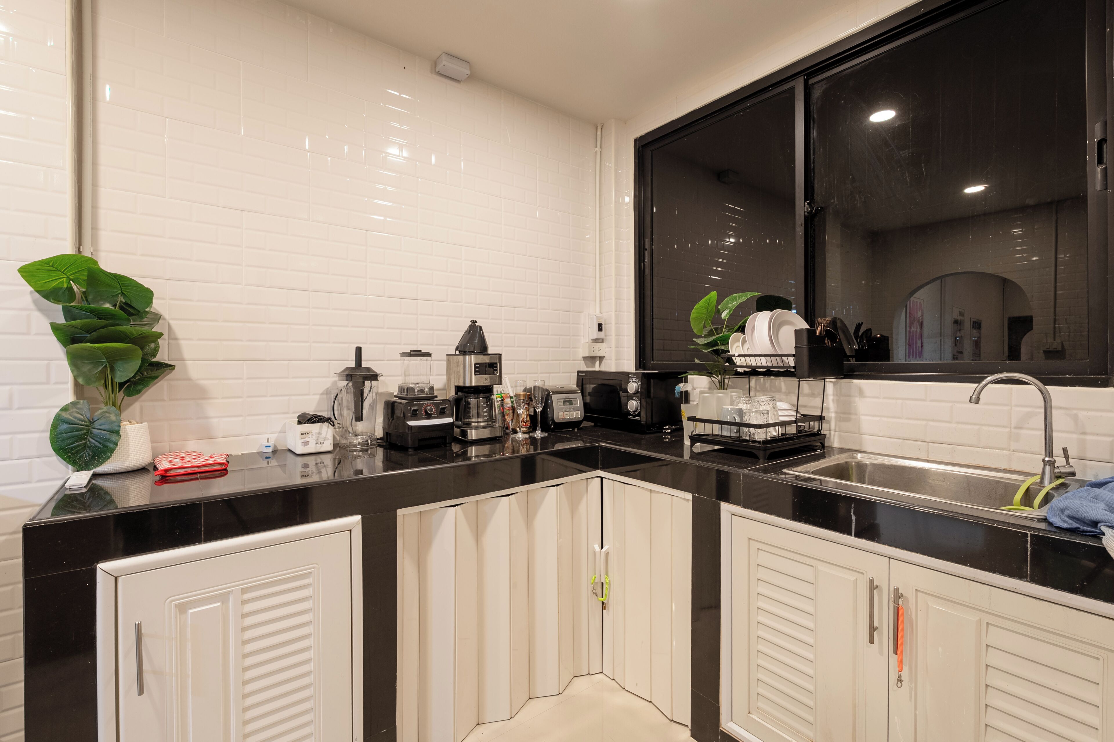 A modern kitchen with white cabinets, a black countertop, and a large window.