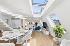 A modern interior with a dining area, kitchen, and living space, featuring skylights and a staircase. - IKON Old Town Penthouse | AC, Lake & Mountain View (Zürich)