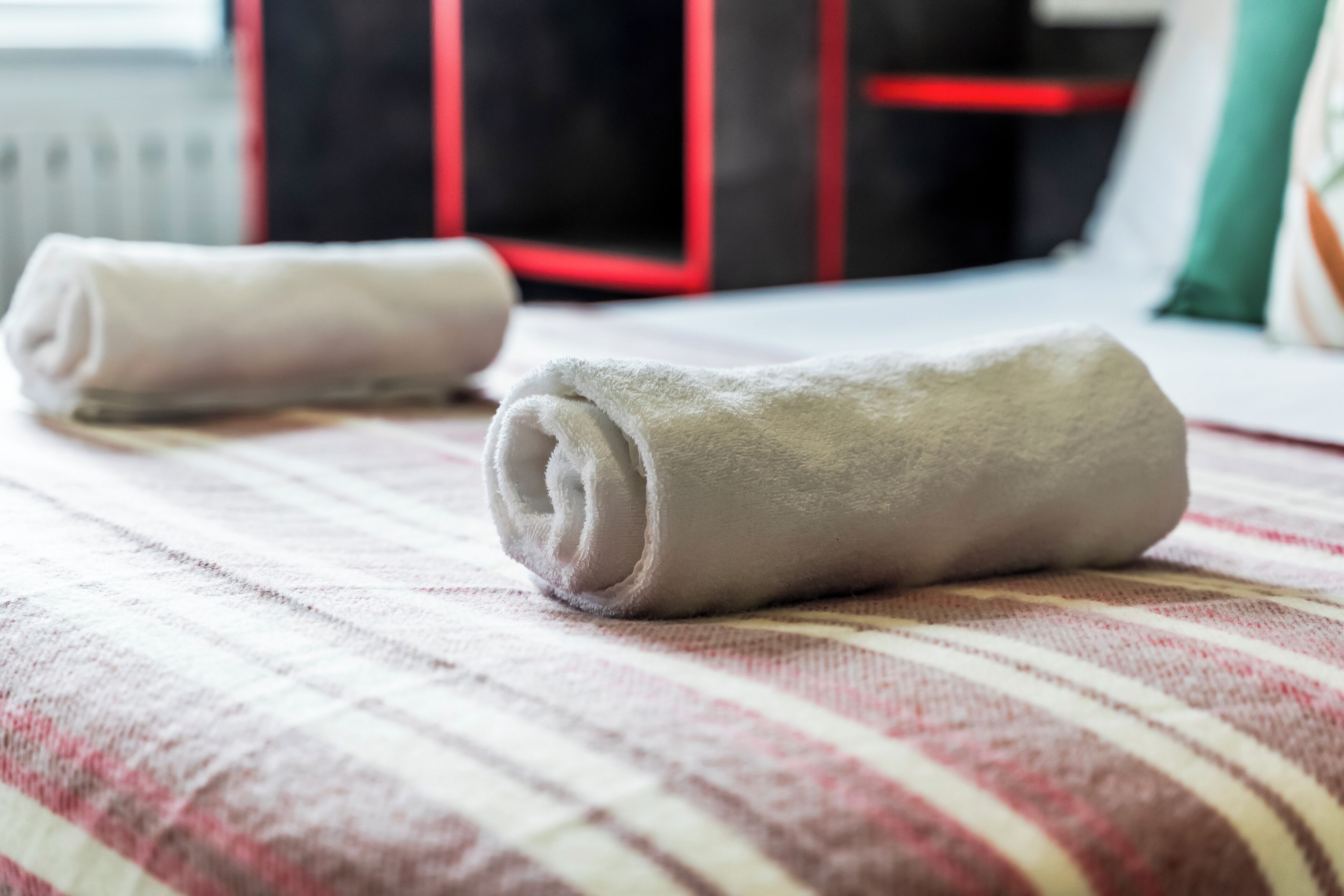 Un lit avec des serviettes enroulées et une couvre-lit à rayures.
