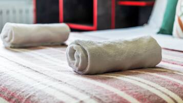 Un lit avec des serviettes enroulées et une couvre-lit à rayures.