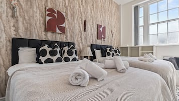 Een hotelkamer met twee bedden, muren met een marmerlook, abstracte kunst en een groot raam.
