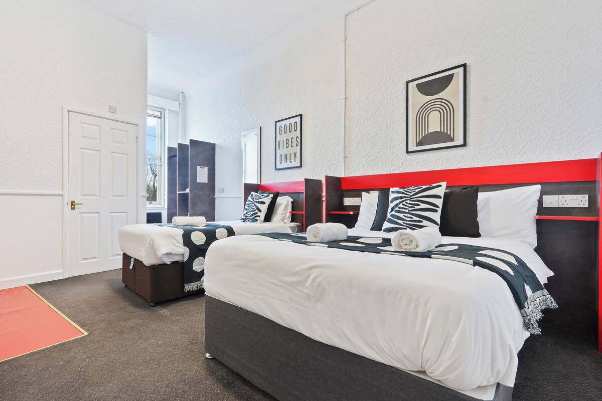 A hotel room with two beds, a red headboard, and a view of the city.