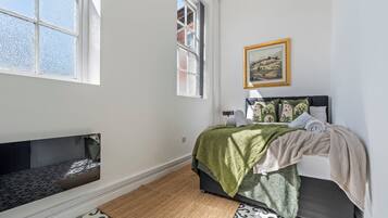 A bedroom with a bed, a window, a painting, and a built-in bench.