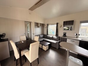 A compact kitchenette with a dining area, a sofa, and a small table. - Mobile home CONFORT le Portel plage chez Nono et Alex (Le Portel)