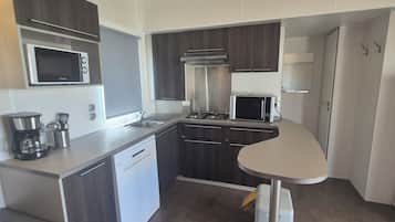 A compact kitchen with a microwave, stove, sink, and a small table.
