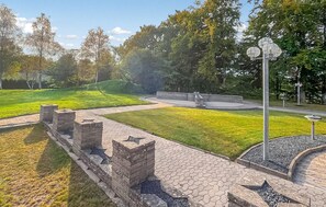 En park med en asfalterad gångväg, stenkonstruktioner och en rund sittplats.