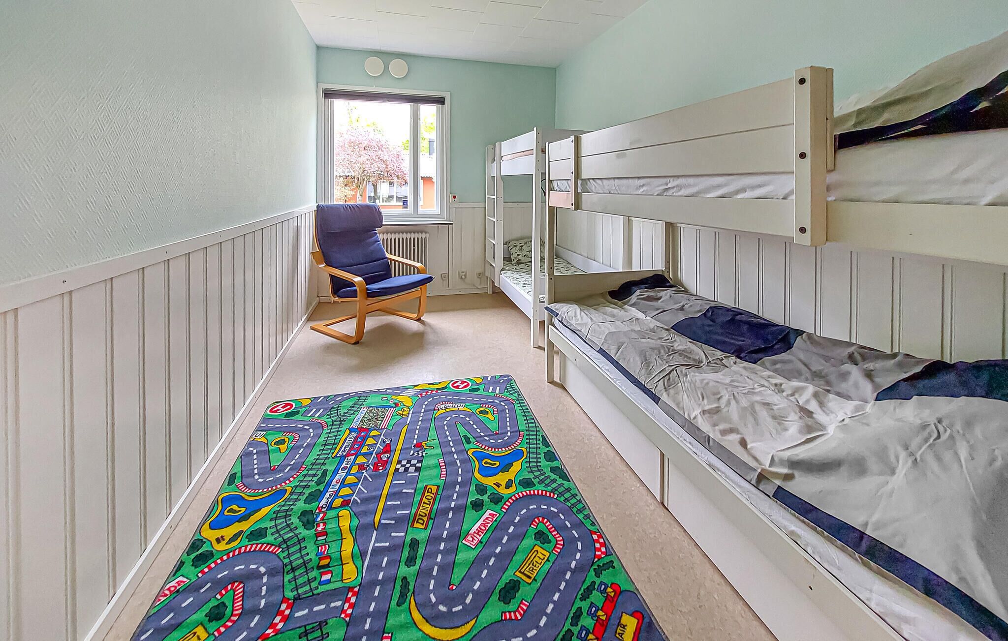 A room with bunk beds, a rocking chair, and a colorful rug.