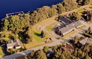 Ett flygbildsbild av ett bostadsområde med hus, en väg och en vattenyta.