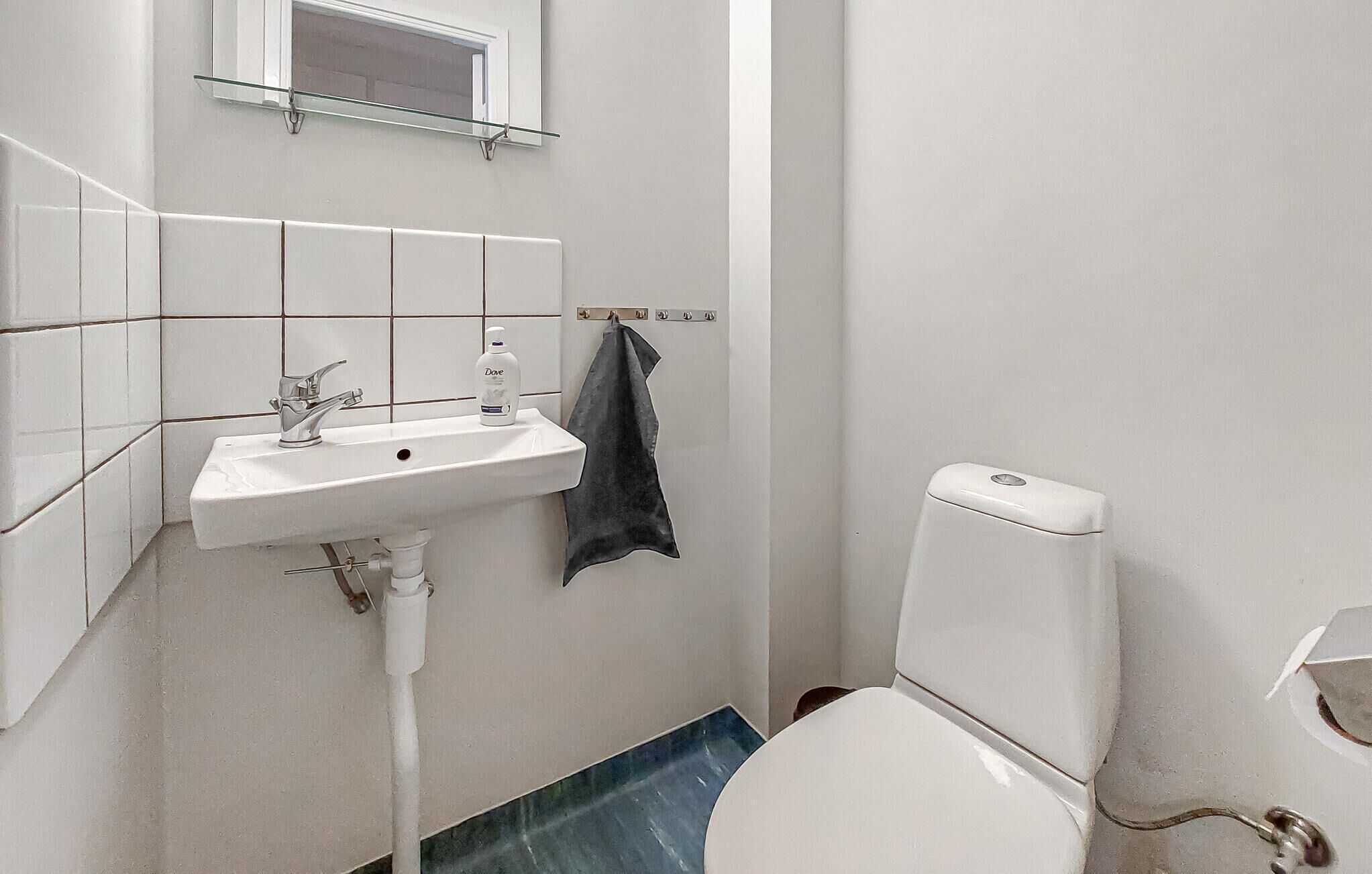A small bathroom with a white sink, a mirror above it, and a toilet.